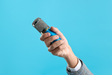 Man with microphone on light blue background, closeup