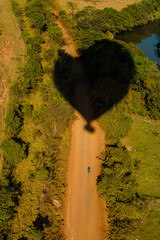 A perfectly defined shadow from a hot air balloon is cast over a golden field, creating a visual composition that combines movement and tranquility. The texture of the dry vegetation, illuminated 