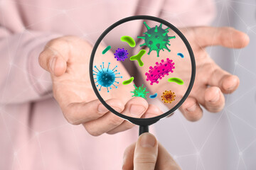 Woman looking at man's hand with magnifying glass, closeup. Illustration of microbes