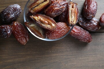 Many tasty dried dates in bowl on wooden table, top view. Space for text