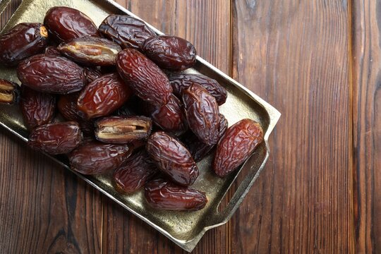Many tasty dried dates on wooden table, top view. Space for text