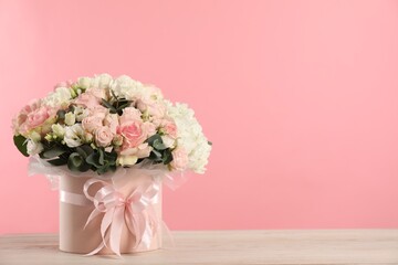 Fototapeta premium Beautiful bouquet in box on wooden table against pink background. Space for text