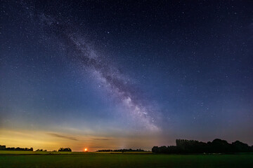Milky way over farm land in Normandy and rising moon, natural countryside landscape under summer starry night, Night of the Stars (Nuit des Etoiles)