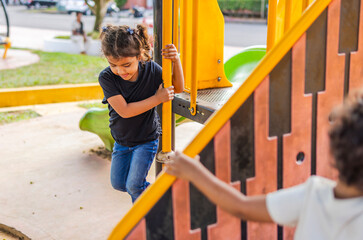 Fototapeta premium Latino children playing in an outdoor playground, enjoying an afternoon outing