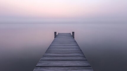 Obraz premium Serene sunrise over calm lake with wooden dock extending into misty water.