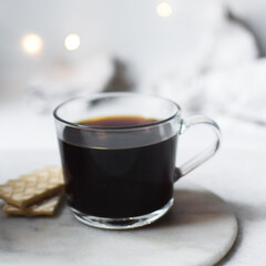 Selective focus on a glass cup with coffee on a white marble tray