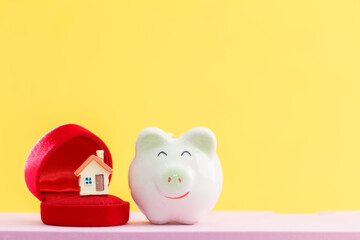 Piggy bank with saving money for wedding and home model put inside put on the desk in the office, Saves money for family with love and planning for future family development concept.