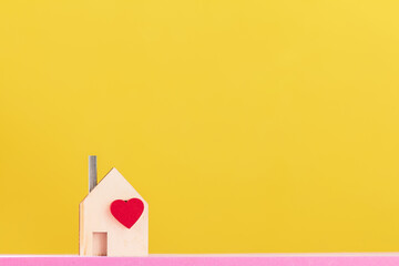 Home model with red heart put on the pink foam on bright yellow color background in the office, The buying a new real estate as a gift to family or the one loved concept.