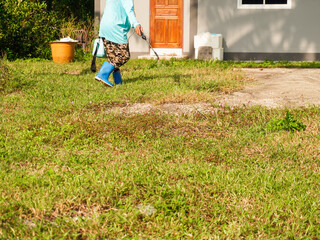 Gardeners in full-coverage clothing spraying herbicides in an outdoor lawn. Spraying to kill weeds....