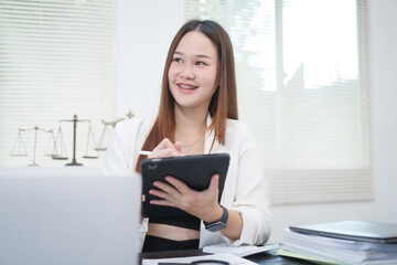 A young, professional businesswoman working at her desk in an office, providing online legal...