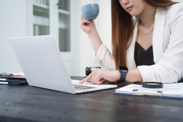 A young, professional businesswoman working at her desk in an office, providing online legal...