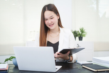 A young, professional businesswoman working at her desk in an office, providing online legal...