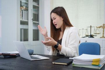 A young, professional businesswoman working at her desk in an office, providing online legal...