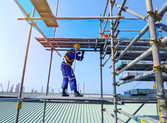Construction worker on scaffolding working on a roof. Roofing and Scaffolding.