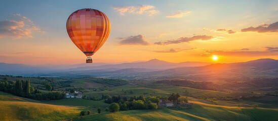 Obraz premium Hot air balloon flying over a scenic landscape at sunset.