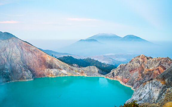 Top of a mountain with a view of turquoise sulfur water lake, surrounded by rock cliff at Kawah Ijen volcano, East Java, Indonesia.