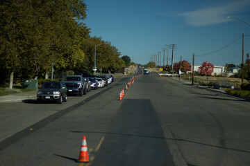 Traffic cones line a road indicating construction zone in a suburban area during daylight