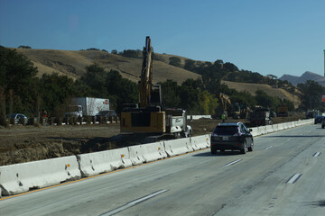 Construction activity along highway near rolling hills under clear sky
