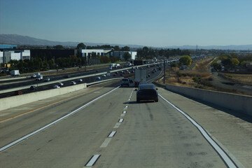 Busy highway filled with vehicles on a sunny day in a suburban area