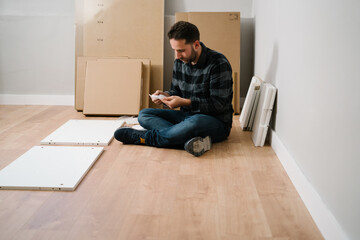 Man sitting on the floor assembling furniture. Do it yourself furniture assembly.