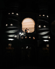 the bride and groom hug and look at each other. They are in a room with soft light that makes them...