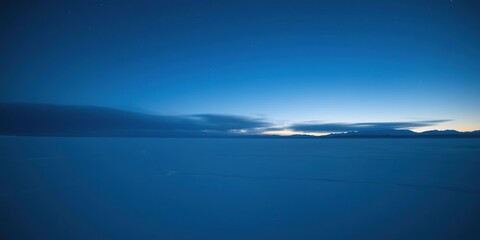 Obraz premium The stunning arctic landscape at night with a vast and calm frozen lake under an endless blue sky, frosty atmosphere, arctic landscape, serene landscape