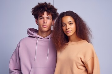 A man and a woman are standing next to each other, both wearing hoodies