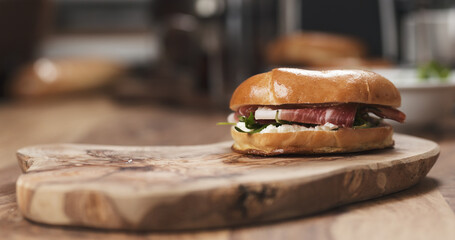 bagel sandwich with prosciutto and cream cheese on wood board