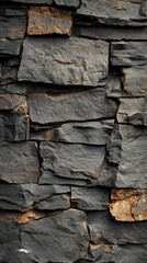 Fototapeta premium A textured wall made of dark, layered stones featuring various sizes and colors.