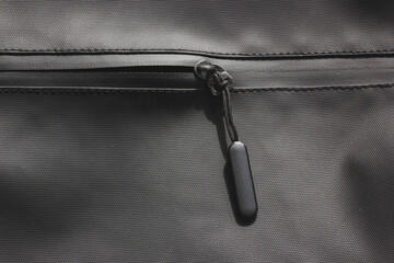 A close-up of a black waterproof zipper on a textured fabric. The zipper is partially open, revealing the soft lining inside.