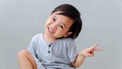 asian boy smiling and showing up two fingers, the peace symbol.