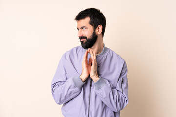 Caucasian man with beard wearing a jacket over isolated background scheming something