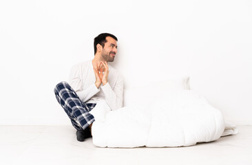 Caucasian man in pajamas sitting on the floor at indoors scheming something