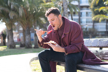 Fototapeta premium Young caucasian man eating sashimi at outdoors
