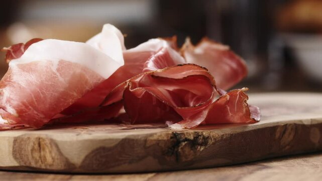 Slow motion prosciutto falling on wood board