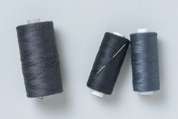 Black grey gray thread spools with needle background with copy space for text close-up flat lay top view