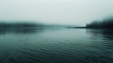 Misty lake view with rippling water below a muted, fog-covered horizon, creating an aura of mystery and serene, infinite calm.