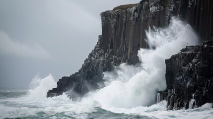 Dramatic waves crash against rugged cliffs in a display of nature's power, surrounded by gray skies, evoking raw coastal energy.