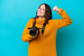 Young photographer woman isolated on blue background doing strong gesture