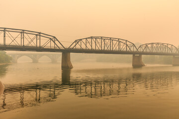 Obraz premium A bridge over a river with a foggy sky in the background