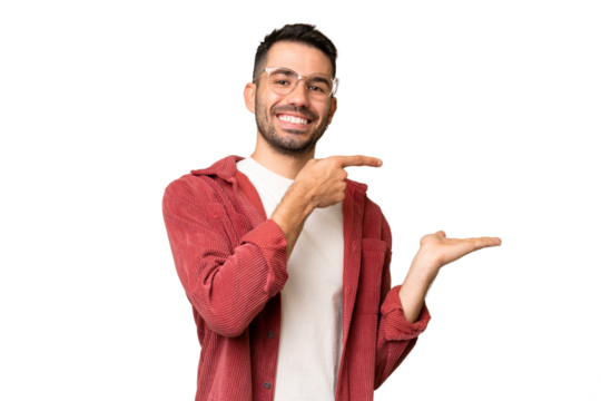 Young handsome caucasian man over isolated chroma key background holding copyspace imaginary on the palm to insert an ad