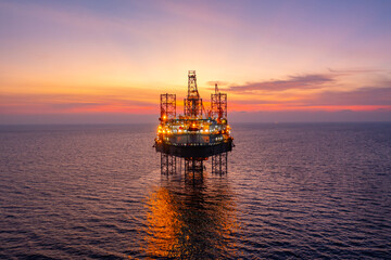 Aerial view of silhouette offshore jack up drilling rig during sunset - oil and gas industry.