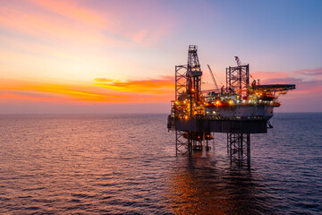 Aerial view of silhouette offshore jack up drilling rig during sunset - oil and gas industry.
