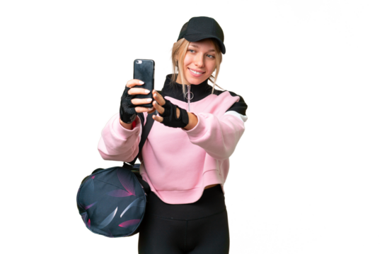 Pretty sport woman with sport bag over isolated chroma key background making a selfie