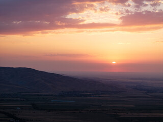 Fototapeta premium Mountain landscape in summer at sunset. Fields and lake near the mountains. Top view, drone photo.
