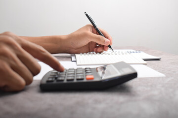 Businessman using a calculator to calculate numbers on a company's financial documents, he is analyzing historical financial data to plan how to grow the company. Financial concept.
