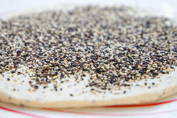 Close-up of dough with flax, black and white sesame seeds. Selective focus.