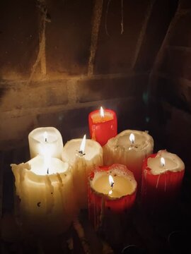 Płonące, wypalone, stare, świece woskowe w starym,  murowanym kominku. Cieknący wosk, stearyna. Pajęczyna. Ciepła, tajemnicza atmosfera.