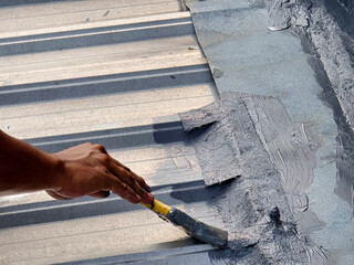 GeneWorkers cover a leaking galvalum roof, apply anti-leak paint and fiber.  coating concrete and steel roof surfaces with waterproof paint.rated image