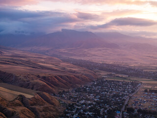 Drone view of the village and mountains at sunset. Beautiful clouds on the sky. Evening landscape.